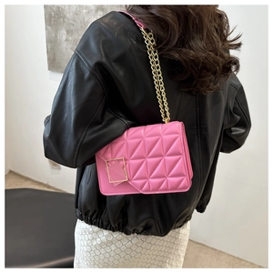 Détail d'un sac bandoulière matelassé rose avec chaîne dorée porté par un mannequin en noir