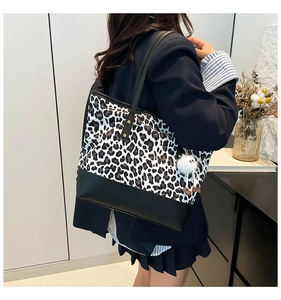 Dettaglio della borsa leopardata con bordo in pelle nera e ciondolo a pompon bianco