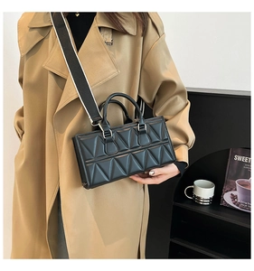 Detail of black quilted crossbody bag with stylish striped wide strap and silver hardware