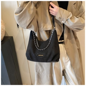 Détail du sac sous le bras croissant en daim noir avec chaîne et écusson mode