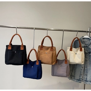Détail de cinq sacs en toile colorés avec poches à bouton-pression et poignées en similicuir