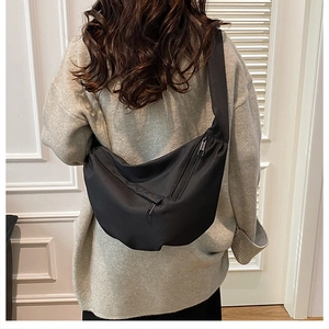 Detailed view of black nylon crescent bag worn over a grey oversized knit sweater