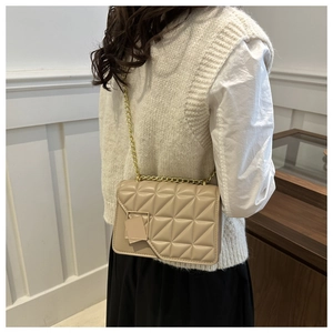 Détail du sac beige matelassé avec bandoulière chaîne dorée et boucle métallique