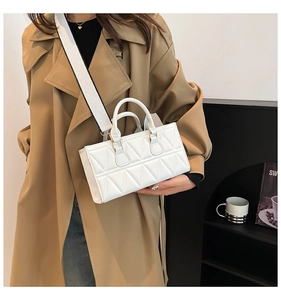 French style white geometric quilted handbag with wide strap worn by model in trench coat