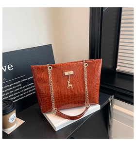 Detail of crocodile pattern leather tote with golden chain strap and deer pendant