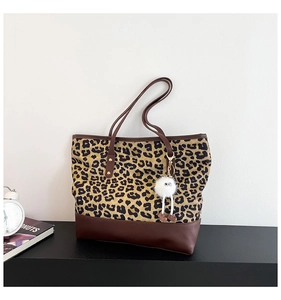 Dettaglio della borsa tote leopardata con base in pelle marrone e charm con pompon bianco