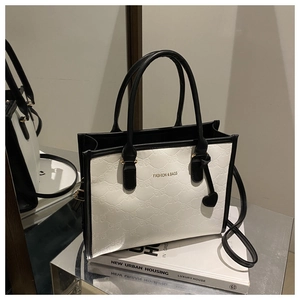 Detail of black and white tote bag with embossed bow patterns and heart charm