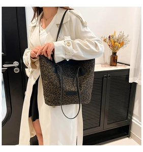 Fashionable leopard print tote bag with black leather straps shown with an elegant trench coat
