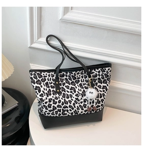 Dettaglio della borsa tote leopardata con base in pelle nera e ciondolo peluche con occhi