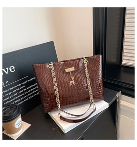 Detail of dark brown faux crocodile tote bag with gold chain strap and deer pendant