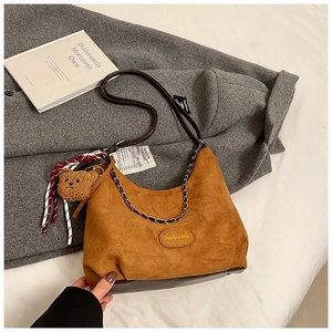 Gros plan détaillé du sac hobo en daim marron avec chaîne en métal et étiquette mode