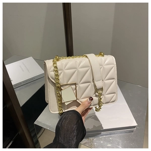 Détail du sac bandoulière beige matelassé avec bandoulière en chaîne dorée et boucle carrée