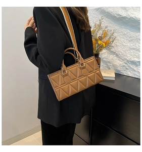 Detailed view of brown quilted handbag with triangle stitching and woven strap