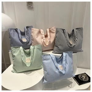 Detail showing five striped canvas tote bags in navy, pink, black, green and blue