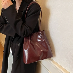 Glossy burgundy patent leather tote bag for women showing a spacious commuter shoulder style