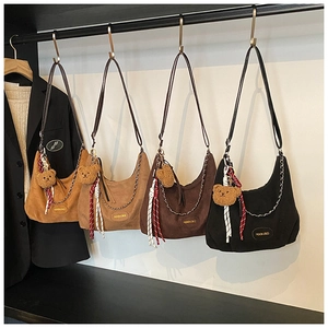 Détail de sacs hobo en daim avec breloque ours et chaîne argentée décorative