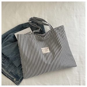 Detailed view of canvas tote bag with black and white vertical stripes and sturdy handles