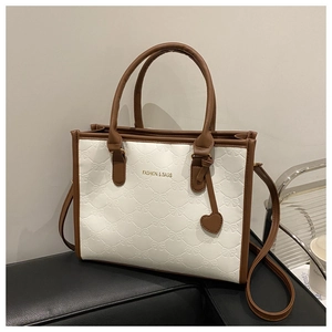 Detail of contrast color tote bag with bow-knot embossed texture and heart charm