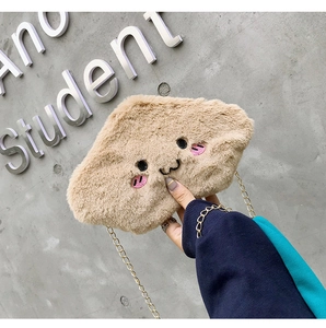 Close-up of khaki plush crossbody bag featuring cute embroidered face and gold chain