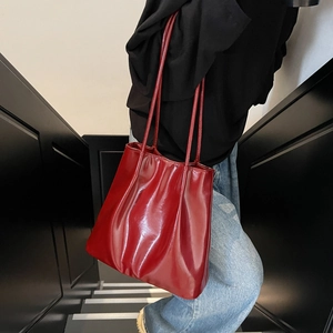 Vintage burgundy glossy leather tote bag for women shown in a street style setting