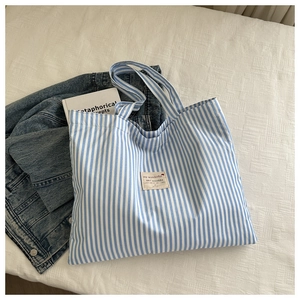 Detail of blue and white striped canvas tote bag with woven label and handles