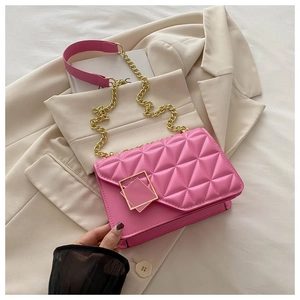 Détail du sac bandoulière rose matelassé avec boucle dorée sur un blazer beige