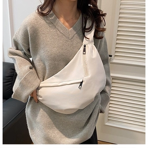 Matte white leather crescent crossbody bag shown on a model wearing a grey sweater
