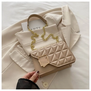 Détail du sac à main matelassé beige avec chaîne dorée et boucle en métal géométrique