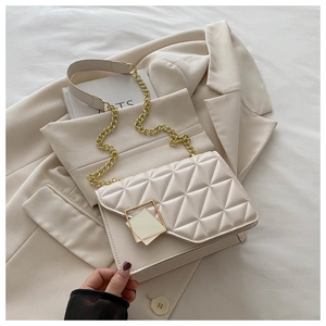 Détail d'un sac bandoulière matelassé crème avec chaîne dorée et boucle métallique carrée