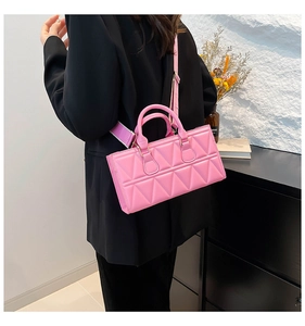 Detail of pink quilted handbag with geometric pattern worn over a black blazer