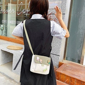 Détail du sac bandoulière en toile avec rabat vert olive et badges d'animaux mignons 3D