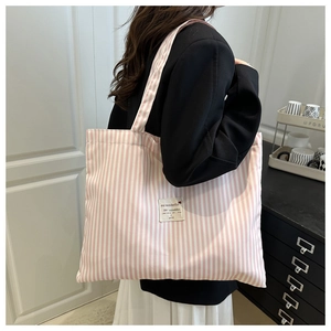 Detailed close-up of a pink and white striped canvas tote bag with a woven brand label
