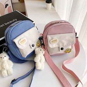 Close-up of nylon canvas mini bags featuring bear charms and cartoon brooches