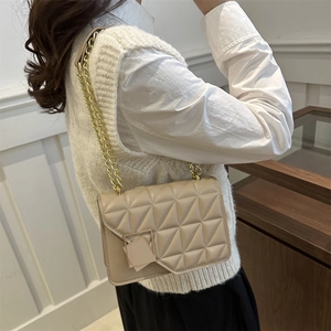 Sac à bandoulière matelassé beige avec surpiqûres géométriques porté par un mannequin