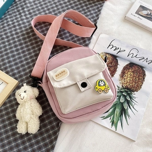 Close-up of pink nylon crossbody bag with cute bread patch and plush bear accessory