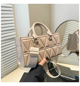 Close-up of beige quilted crossbody bag with wide shoulder strap and round handles