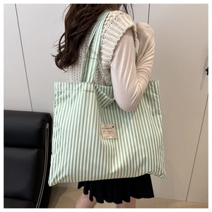 Detailed view of large green and white striped canvas tote bag with woven logo label