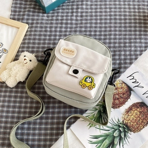 Detail of cute nylon crossbody bag with Bread Pompom embroidery and teddy bear charm