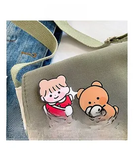 Gros plan de pins mignons de dessin animé sur un sac à bandoulière en toile verte