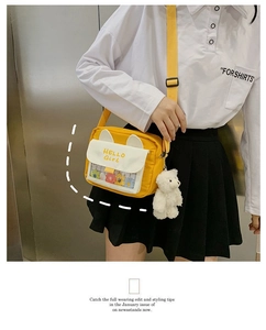 Detail of yellow canvas crossbody bag featuring a clear flower pocket and plush bear charm
