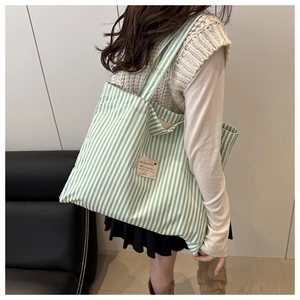 Detail of green and white striped canvas tote bag showing wide straps and fabric label