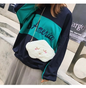 Close-up of white plush cloud bag with cute smiling embroidery and gold chain strap