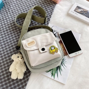 Detail of sage green nylon mini crossbody bag with cloud patch and plush bear charm