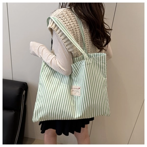 Green and white striped canvas tote bag shown worn on shoulder for daily commute