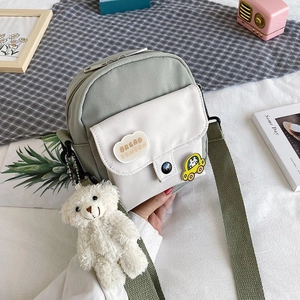 Close-up of small nylon canvas crossbody bag with cute plush bear charm and pins