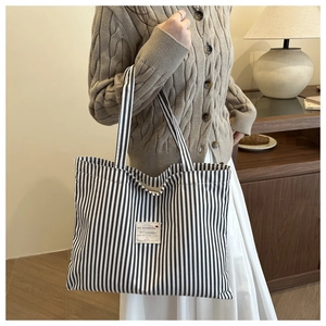 Detail view of large striped canvas tote bag with shoulder strap for daily commuting