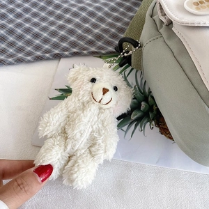 Detail of cute white teddy bear plush keychain on light green canvas crossbody bag