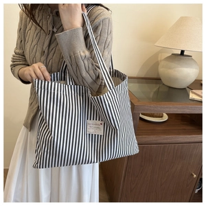 Detail of striped canvas tote bag with decorative patch and durable fabric texture