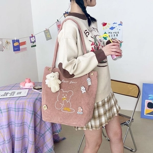 Détail d'un sac fourre-tout en velours rose avec broderie ours et porte-clés décoratif