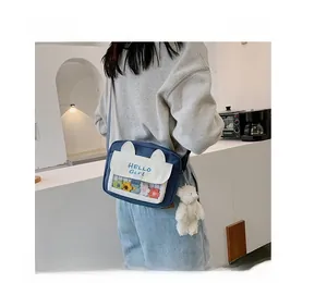 Detail of blue and white canvas crossbody bag with cat ear design and plush bear charm